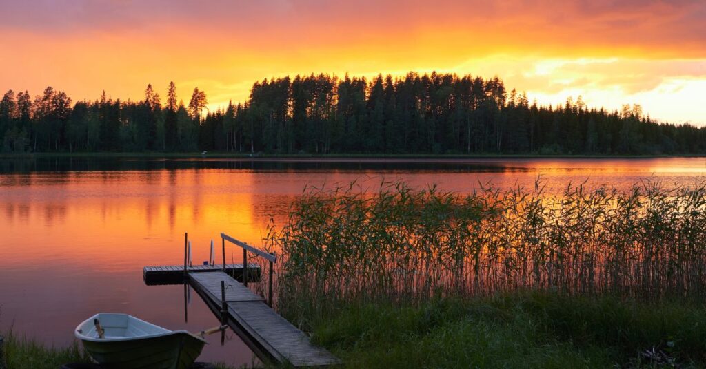 Kesälomaa viettävä henkilö rentoutumassa ilman työvälineitä järven rannalla