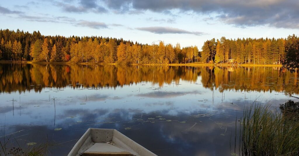 Soutuvene tyynellä järvellä syksyisessä ilta-auringossa – työaikalaki turvaa lepoajat.